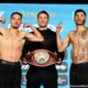 Two light welterweight fighters flex on the scale during an official weigh-in as an official stands between them holding a championship belt.