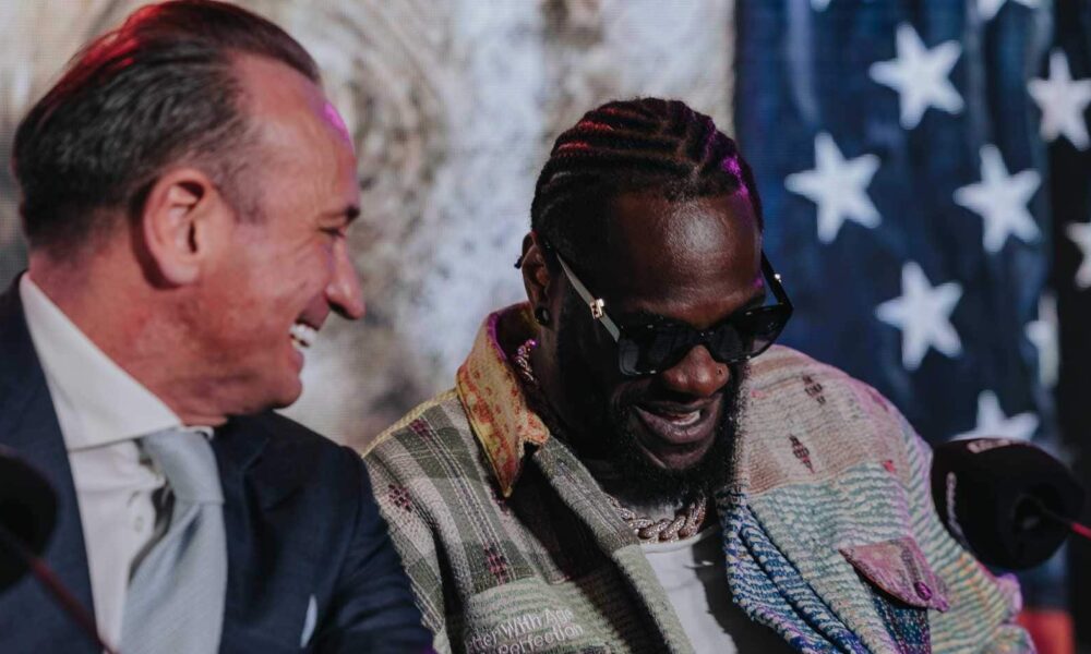 Deontay Wilder laughs with Kalle Sauerland during a press conference ahead of his fight with Derek Chisora