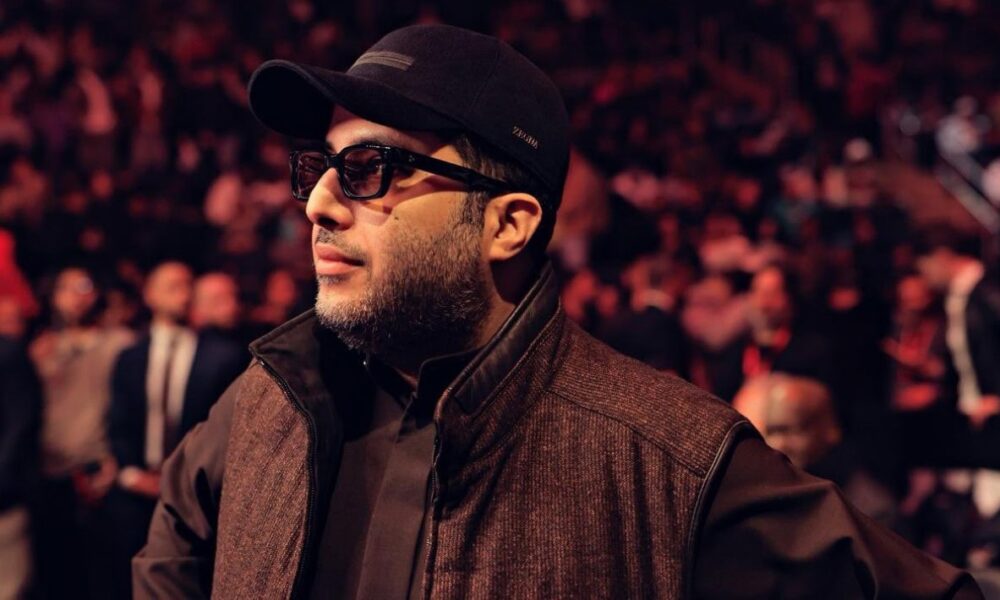 Turki Alalshikh attends a major boxing event, standing ringside in front of a packed arena crowd.