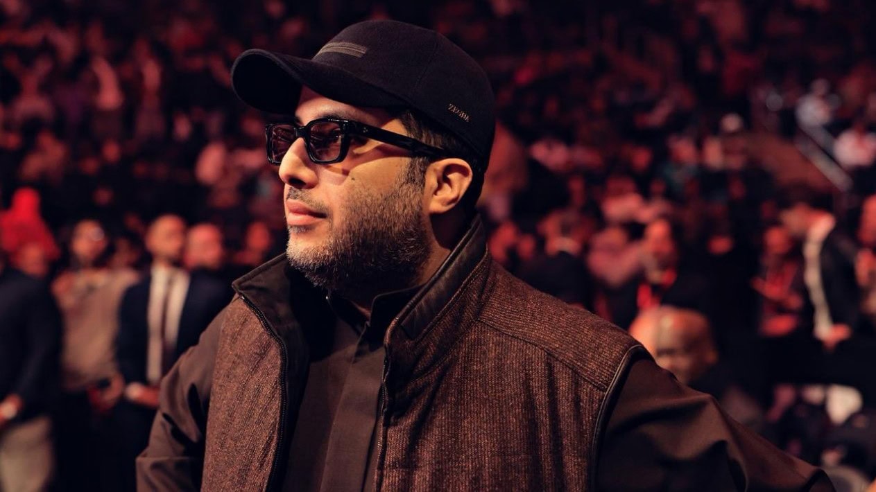 Turki Alalshikh attends a major boxing event, standing ringside in front of a packed arena crowd.