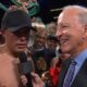 David Benavidez celebrates a dominant victory over Gilberto Ramirez at T-Mobile Arena, holding multiple WBC belts while giving a post-fight interview, with his team cheering in the background.