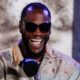 Deontay Wilder smiles during a media appearance with a United States flag behind him