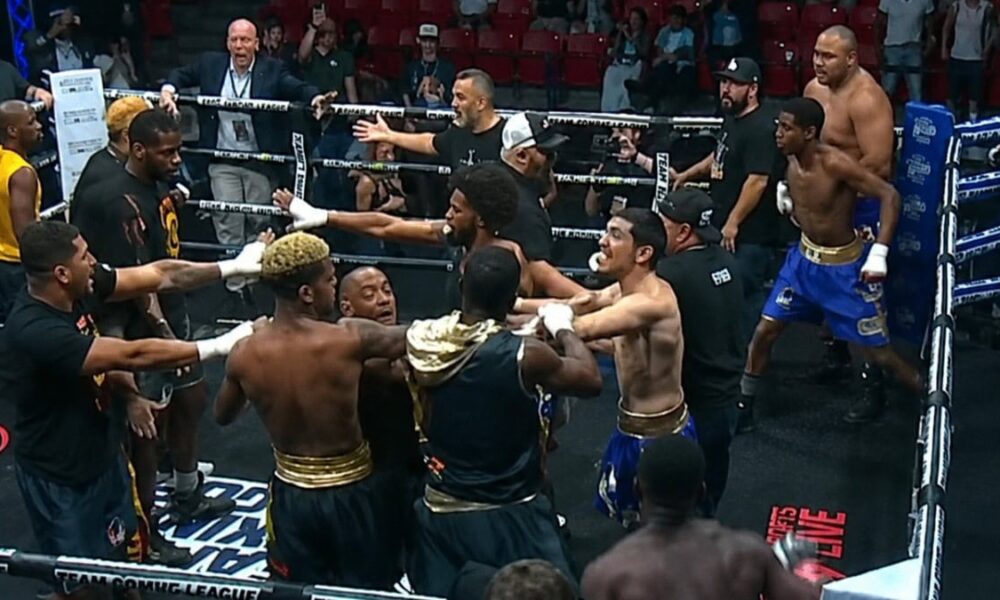 Multiple boxers and team members confront each other inside the ring during a Team Boxing League event as officials attempt to separate them in the chaos