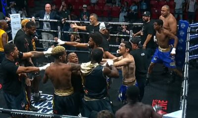 Multiple boxers and team members confront each other inside the ring during a Team Boxing League event as officials attempt to separate them in the chaos