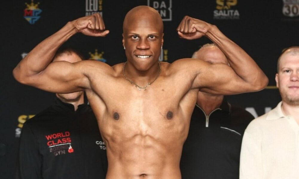 Atif Oberlton flexes during an official weigh-in with Dmitriy Salita standing behind him.